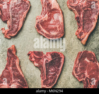 Flat-lay di crudo fresco di carne di manzo bistecche e sfondo grigio Foto Stock