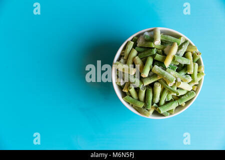 Fagiolini surgelati verdure nella ciotola in bianco su sfondo blu Foto Stock