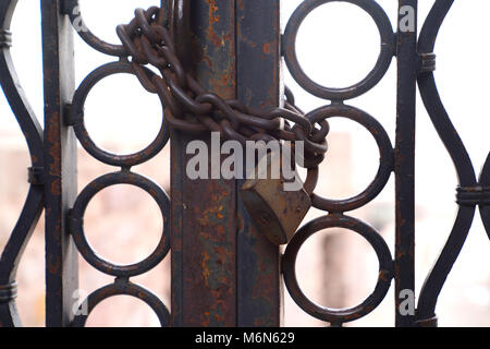 Primo piano porta di metallo bloccato con una catena e un lucchetto arrugginito Foto Stock