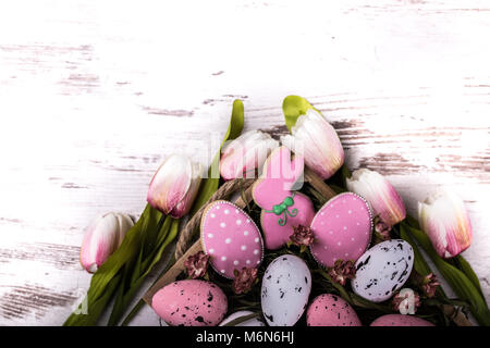 Pasqua gingerbread cookie e bel bouquet di tulipani su un tavolo di legno. Il coniglio e le uova. Biglietto di auguri. Vista da sopra.Copia dello spazio. Foto Stock