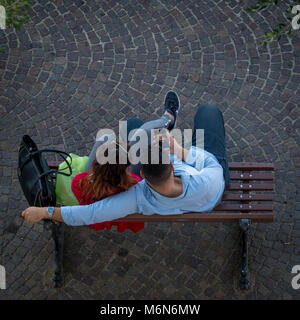 Giovane seduto su un banco di lavoro guardando il telefono cellulare dal di sopra Foto Stock