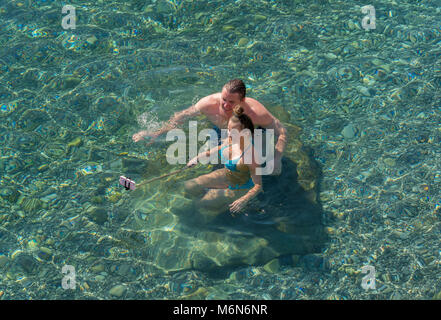 Coppia giovane in mare tenendo selfie con telefono cellulare su un bastone selfie Foto Stock