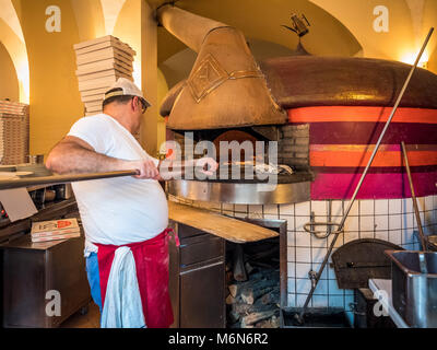 Pizzaiolo lavora con un tradizionale forno a legna Foto Stock