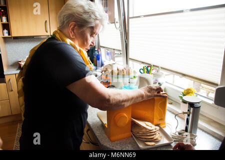 Germania donne anziane uso affettatrice pane o pane di taglio taglierina pane in cucina in casa il 10 settembre 2017 a Heidelberg, Germania Foto Stock