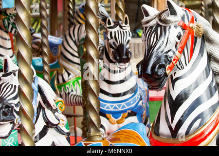 Primo piano di zebre colorate e dipinte con colori vivaci durante un giro in carosello della zona fieristica britannica tradizionale. Giro in giostra nel Regno Unito. Foto Stock