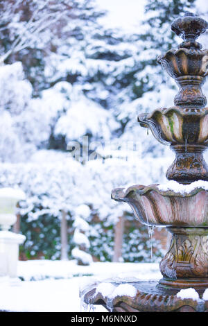 Close up, ritratto cattura di acqua congelata fontana isolato all aperto con appeso ghiaccioli, ornato giardino nevoso. Inverno magico paese delle meraviglie scena. Regno Unito. Foto Stock