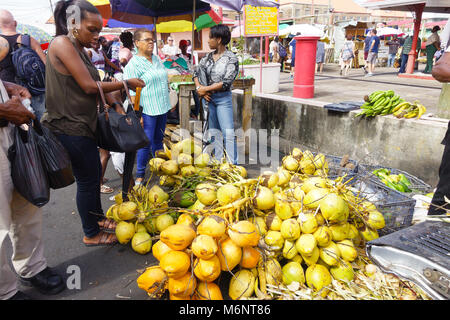 Fresche, giallo arancio e verde noci di cocco in vendita su un mercato del venerdì al St George's sull'isola caraibica di Grenada Foto Stock