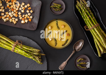 Crema di asparagi la zuppa in una ciotola su sfondo nero Foto Stock