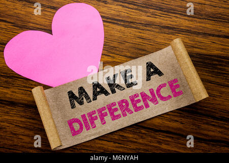La scrittura di un testo che mostra di fare la differenza. Il concetto di business per il successo di motivazione scritta su una nota adesiva carta, sullo sfondo di legno. Con cuore rosa meani Foto Stock