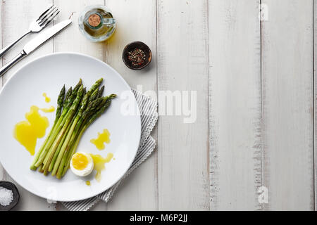 Asparagi al forno con uova sode o in grande piastra bianca su sfondo di pietra, vista dall'alto Foto Stock