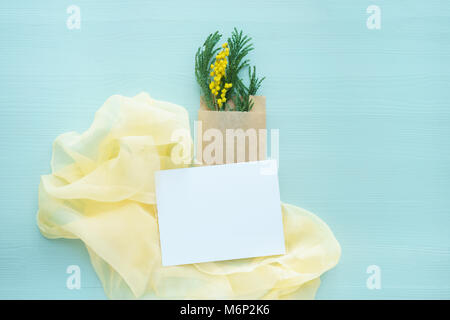 La Mimosa brunch nella busta Kraft bag in blu su uno sfondo di colore giallo di seta bianca con la scheda vuota per il testo Foto Stock
