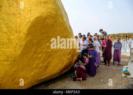 Gli uomini stanno mettendo le foglie d'oro sulla Kyaiktiyo Pagoda, il Golden Rock, alla sommità del Mt. Kyaiktiyo è uno dei più importanti luoghi di pellegrinaggio dell' Foto Stock