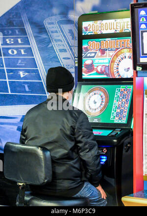 Uomo maturo utilizzando fixed odds Roulette macchina in Bookmakers. Londra, Inghilterra, Regno Unito. La macchina descritta come la cocaina crack del gioco d'azzardo Foto Stock