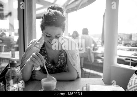 Ragazza a bere caffè e sorridente in bianco e nero Foto Stock