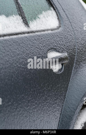 Grigio scuro porta auto coperto di ghiaccio nero su un sub zero inverno mattina causato dalla pioggia gelata. Copia di potenziale spazio a sinistra della maniglia della porta. Foto Stock