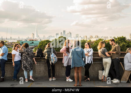 La gente di socializzare e gustare un drink insieme a Franchi outdoor cafe bar sul tetto con vista della città. Foto Stock