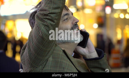 Bello gentleman su smart cell mobile phone in New York City sventolando taxi o incontrare gli amici di notte a Manhattan. Utilizzando la tecnologia GPS per trovare loca Foto Stock