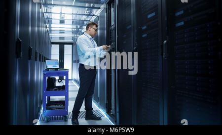 Tecnico IT di installare i dischi rigidi in lavoro Server Rack. Sta lavorando nel centro dati. Foto Stock