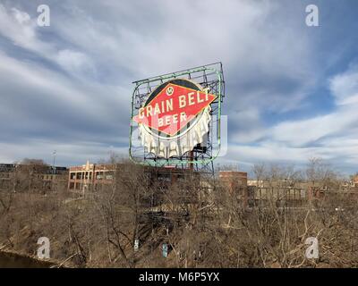 Minneapolis, MN - Circa 2017: cinghia grano birra segno iconico in Minnesota si erge sopra i tetti della città oltre il Fiume Mississippi Foto Stock