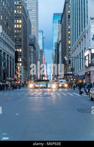 New York City - Circa 2017: vista uptown 7th Avenue a Manhattan durante le ore di punta i pendolari. La gente che camminava crosswalk street come traffico attende al paglierino rosso Foto Stock