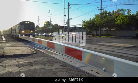 Long Island, NY - Circa 2017: LIRR Ferrovia di Long Island viaggiare in treno ad alta velocità che passa di sfocatura di sicurezza porta di attraversamento di banchina della stazione pick up passenge Foto Stock