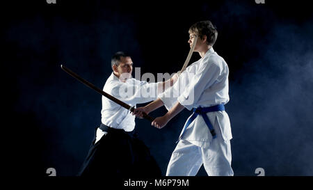 Arti marziali Master insegna ai suoi giovani studenti come lotta con la spada in legno Bokken. Il combattimento termina in pochi secondi, Master vince. Colpo è la schermata isolato Foto Stock