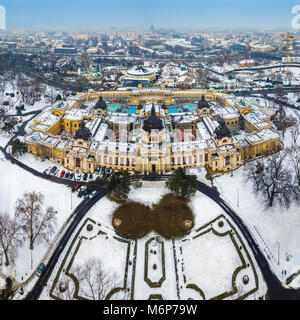 Budapest, Ungheria - Antenna vista sullo skyline del famoso Szechenyi bagno termale nel parco cittadino (Varosliget) su un nevoso inverno mattina Foto Stock