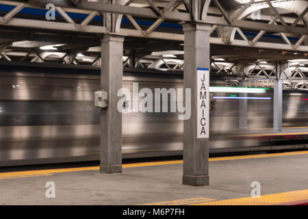 Long Island, NY - Circa 2017: lunga esposizione Giamaica railroad station terminal platform express treno passa attraverso occupato il trasferimento di massa hub di transito Foto Stock