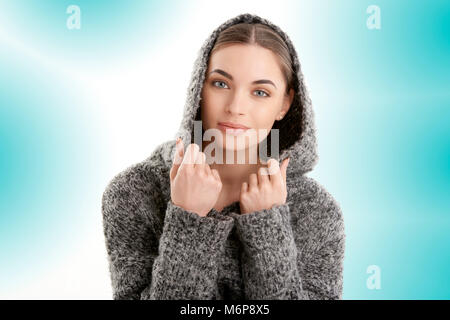 Close-up studio Ritratto di giovane e bella donna che indossa hoodie mentre che pongono in luce isolato sfondo blu. Foto Stock