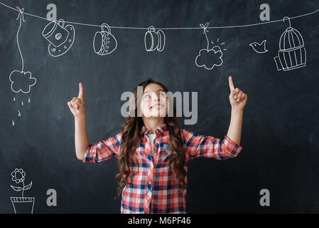 Ragazza creativa che mostra il suo nuovo disegno inusuale e guardando eccitato Foto Stock