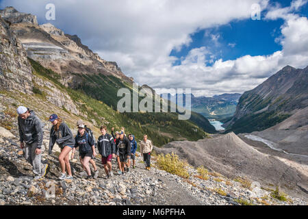 Gruppo di studenti sulla pianura del sei ghiacciai sentiero inferiore su Ghiacciaio Victoria, il Lago Louise in distanza, il Parco Nazionale di Banff, Alberta, Canada Foto Stock