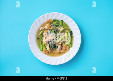 Vista superiore del famoso noodles fritti con carne di maiale, cavolo cinese e i broccoli. Isolato su sfondo blu e il tracciato di ritaglio Foto Stock