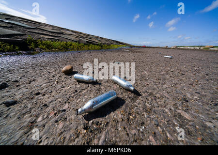 Scartato 'whippits' o hippy crack di protossido di azoto gas esilarante caricabatterie, utilizzato per una elevata attività ricreative, su Harrington shore in Cumbria, nel Regno Unito. Foto Stock