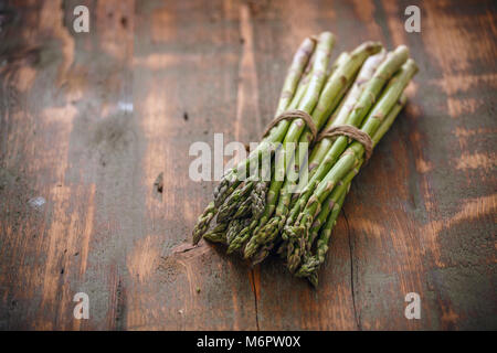 Freschi asparagi verdi grappoli su rustico sfondo di legno Foto Stock