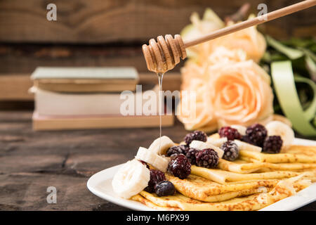 Frittelle di banane e frutti di bosco surgelati su sfondo scuro. crepes con le banane e la frutta Foto Stock