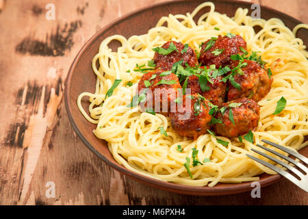 Spaghetti polpette di carne con salsa di pomodoro, erbe su sfondo di legno. Foto Stock