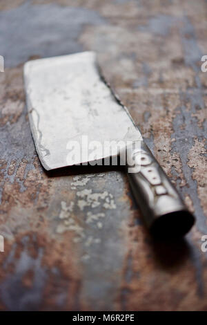 Grande la cucina dello chef coltello cleaver vintage in distressed la superficie del tavolo Foto Stock