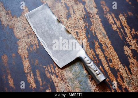 Grande la cucina dello chef coltello cleaver vintage in distressed la superficie del tavolo Foto Stock