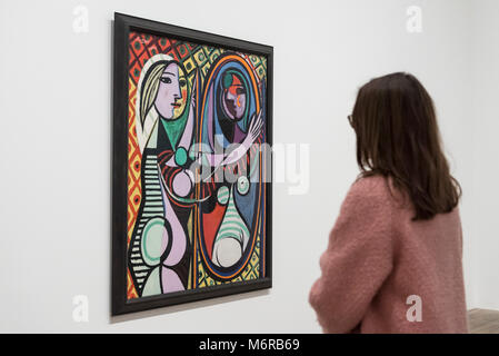 Londra, Regno Unito. 6 marzo 2018. Un visitatore visualizza "Girl prima di uno specchio (jeune fille devant onu miroir)", 1932, di Pablo Picasso. Anteprima di "Picasso 1932 - amore, fama, tragedia', la Tate Modern la prima mostra personale del lavoro di Pablo Picasso. Più di 100 dipinti, sculture e opere su carta che copre l'anno 1932, un tempo di pivotal di Picasso la vita, sono sul display 8 Marzo al 9 settembre 2018. Credito: Stephen Chung / Alamy Live News Foto Stock