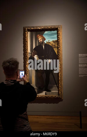 Amsterdam, Paesi Bassi. 6 Marzo, 2018. Un visitatore al Rijksmuseum a piedi attraverso la mostra 'High Society", che apre il 08 marzo 2018, e la fotografia di un dipinto del Moretto da Brescia. Ritratti di potenti principi, eccentrico aristocratici e ricchi borghesi di epoche differenti può essere visto fino al 03 giugno 2018. Foto: Jeroen Jumelet/dpa - ATTENZIONE I REDATTORI: solo uso editoriale in connessione con le attuali relazioni sulle esposizioni. Credito: dpa picture alliance/Alamy Live News Foto Stock