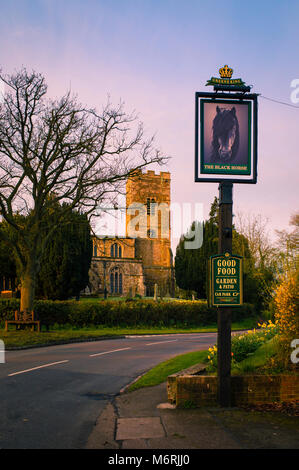 Il cavallo nero pub segno e la chiesa del paese a Foxton. Foto Stock