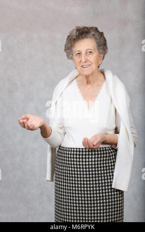 Senior donna tra 70 e 80 anni sta mostrando qualcosa di Foto Stock