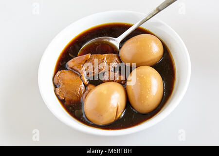 Le uova sode e la carne di maiale e il tofu nella dolce marrone salsa gravy sullo sfondo bianco (Thai è denominato Kai-Pa-Lo)- vista superiore Foto Stock