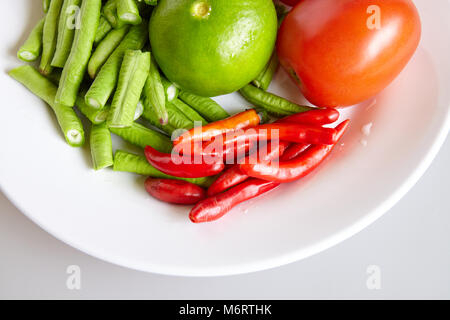 Le materie di ingredienti freschi per il cibo tailandese per produrre lunghe insalata di fagioli, pomodoro, calce - vista superiore, chiusa Foto Stock