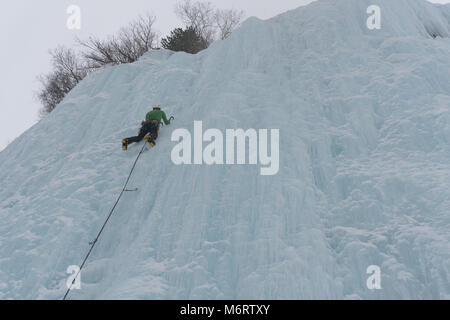Ice Climber su una ripida cascata ghiacciata in profonda inverno nelle Alpi in Svizzera Foto Stock