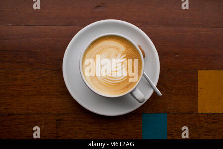 Latte art su una geometrica in legno tavolo da caffè con un blu e quadrato giallo dettaglio Foto Stock