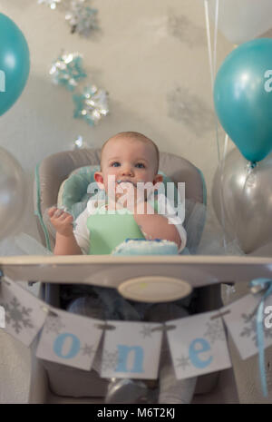 Vista dettagliata del disordine bambina in alta sedia di mangiare prima torta di compleanno a parte Foto Stock