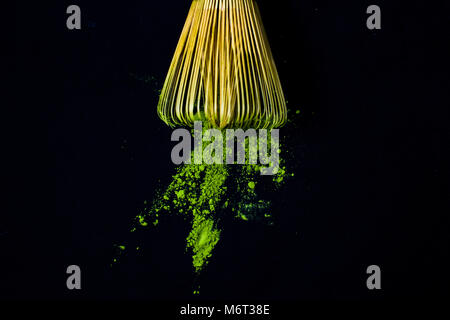 Close up frusta di bambù e il tè verde Matcha polvere su sfondo nero. Foto Stock
