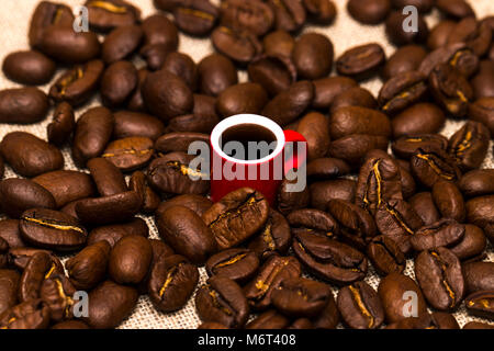 Coppa piena di chicchi di caffè sul panno del sacco, primo piano Foto Stock