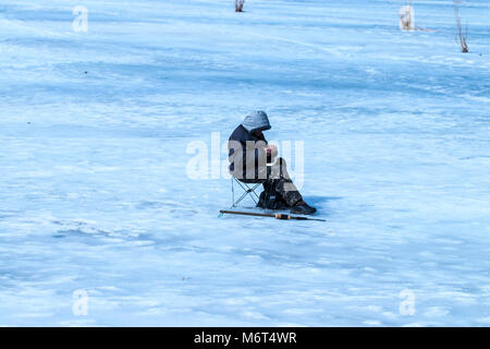 Uomo anziano è stata la pesca in inverno sul lago. Foto Stock